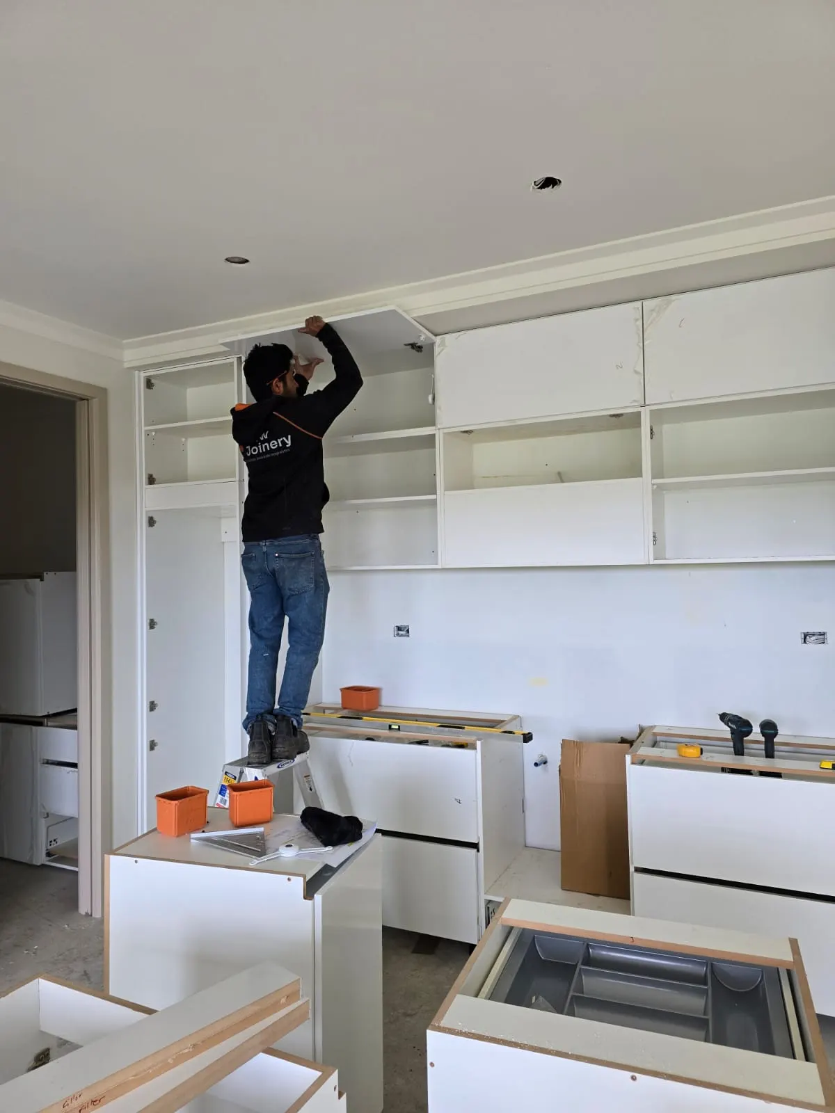 Flow Joinery team member installing overhead kitchen cabinets