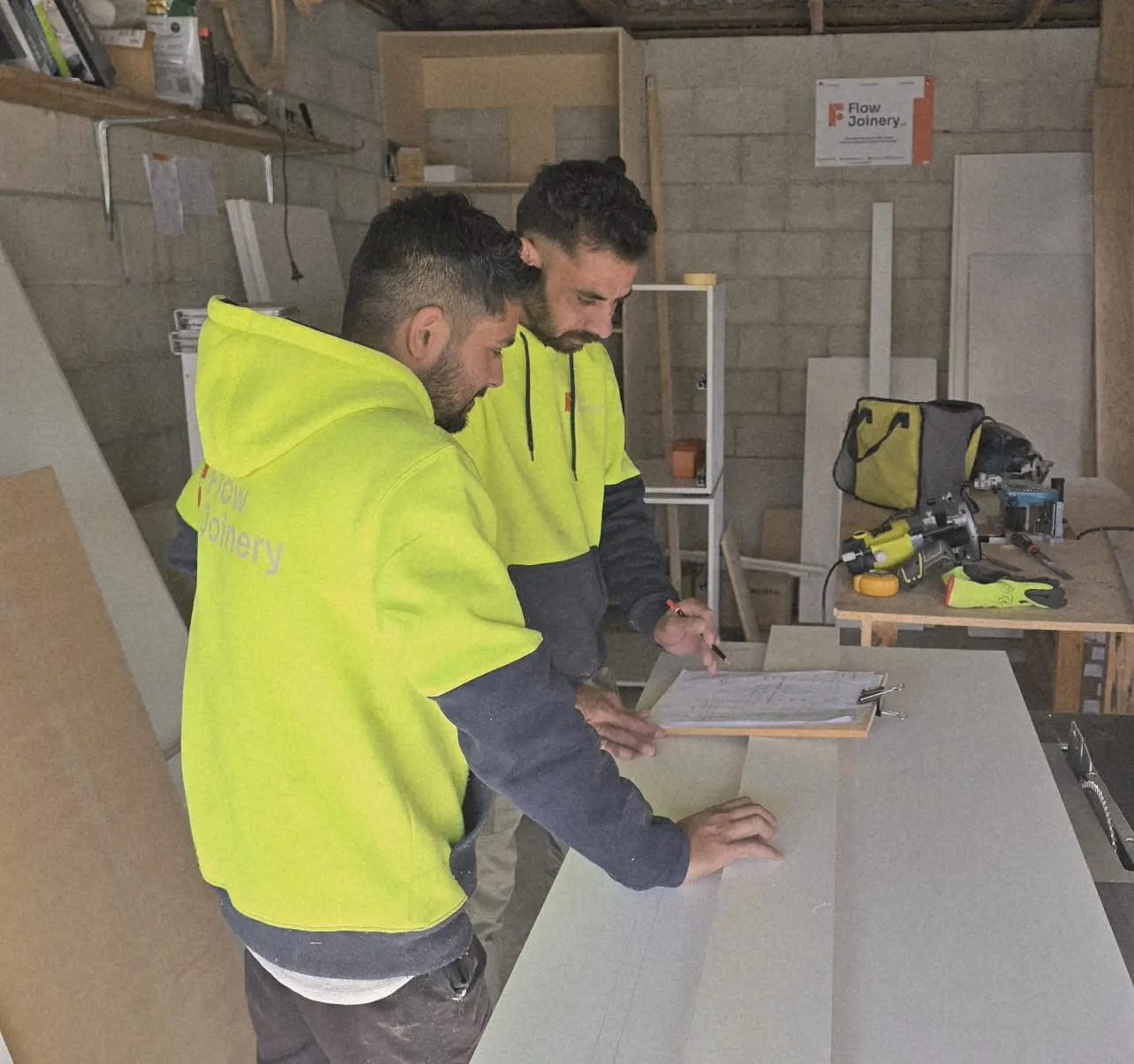 Two Flow Joinery team members reviewing project plans in the workshop