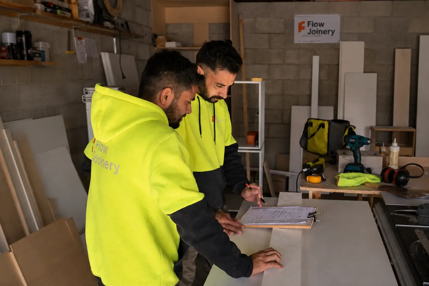 Flow Joinery team reviewing project plans at the workshop bench
